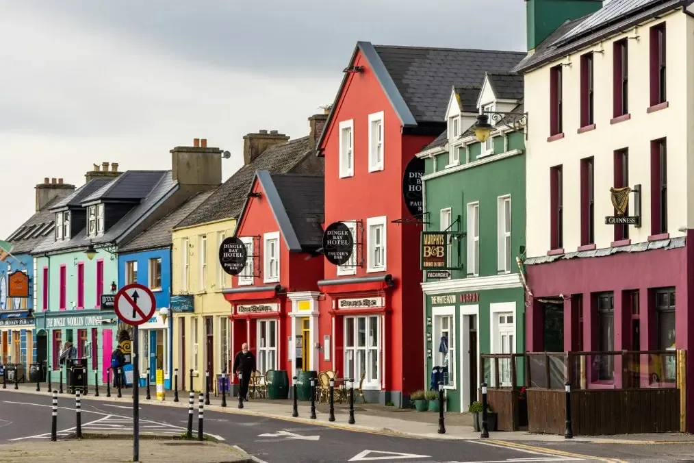 A terrace of brightly painted shops, pubs and guesthouses along a street in Dingle
